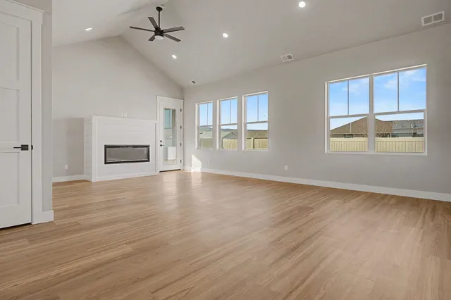 an empty room with wooden floor cabinet and windows