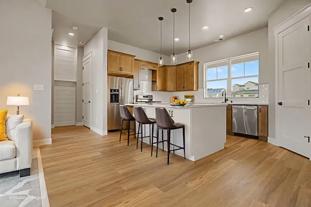 a kitchen with stainless steel appliances a dining table chairs refrigerator and microwave