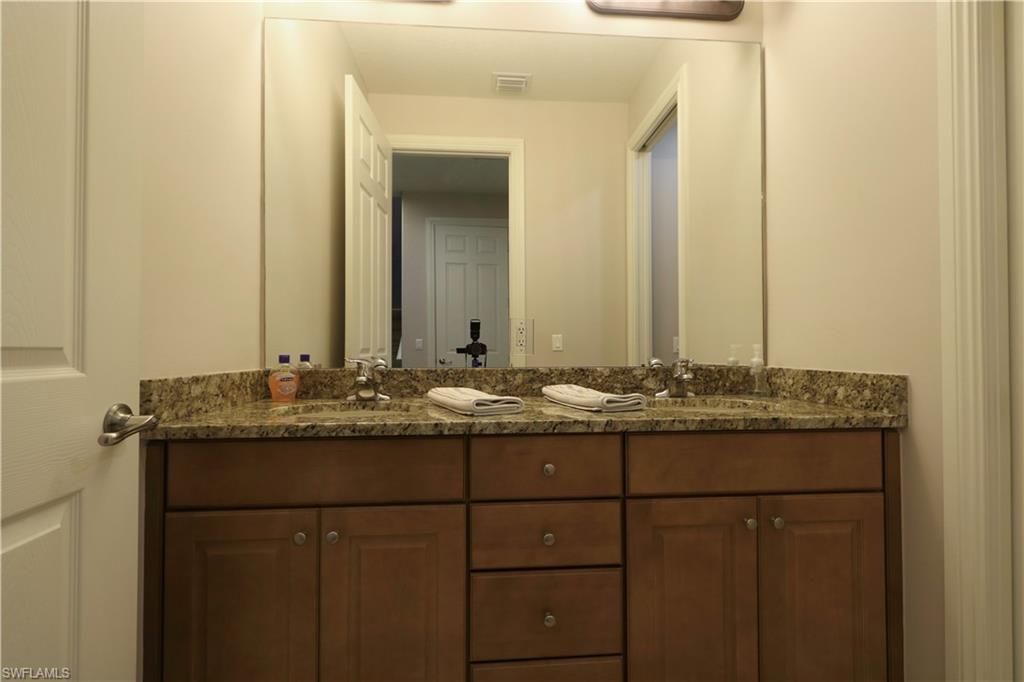 9114 Capistrano Street South, Unit 8501 Naples, FL 34113 - Photo 11 of 26 a bathroom with a granite countertop sink and a mirror