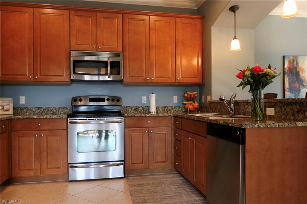 9114 Capistrano Street South, Unit 8501 Naples, FL 34113 - Photo 4 of 26 a kitchen with stainless steel appliances granite countertop a stove a sink dishwasher and a microwave oven with white cabinets