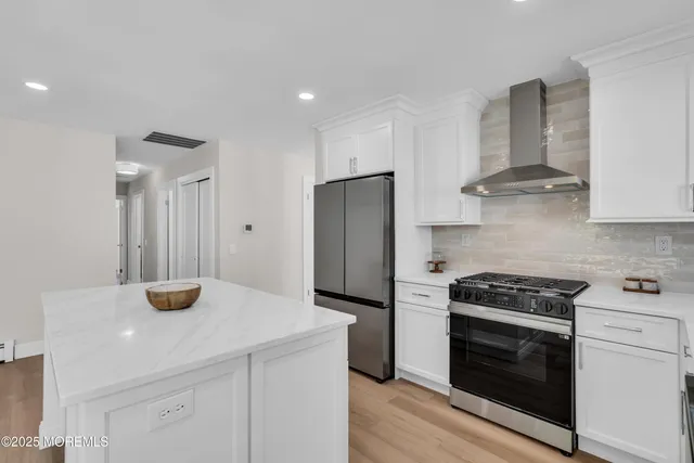 a kitchen with stainless steel appliances a stove and white cabinets