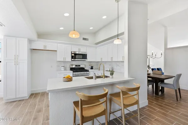 a kitchen with stainless steel appliances a dining table chairs refrigerator and microwave