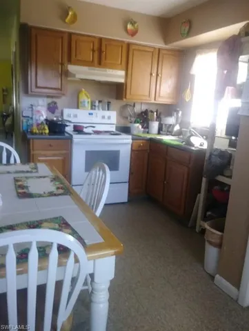 a kitchen with stainless steel appliances granite countertop a table chairs sink and cabinets