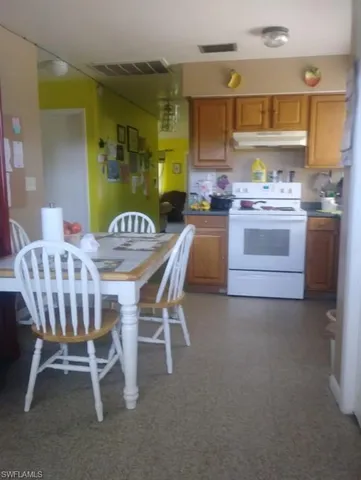 a kitchen with stainless steel appliances kitchen island granite countertop a table chairs and a refrigerator