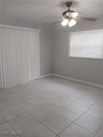 an empty room with windows and fan
