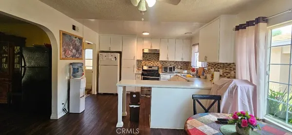 a kitchen with stainless steel appliances granite countertop a refrigerator a stove a sink dishwasher and a dining table with wooden floor