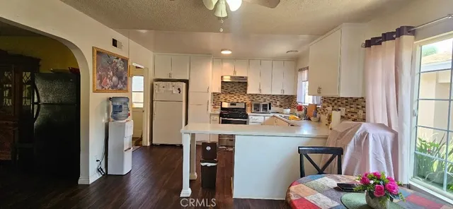 a kitchen with stainless steel appliances granite countertop a refrigerator a stove a sink dishwasher and a dining table with wooden floor