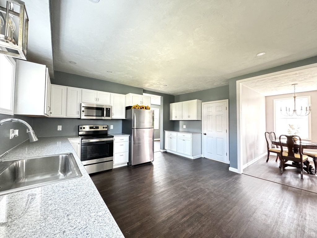 11 Main Street Brookfield, MA 01506 - Photo 5 of 29 a kitchen with stainless steel appliances granite countertop a refrigerator a stove top oven a sink dishwasher and white cabinets with wooden floor