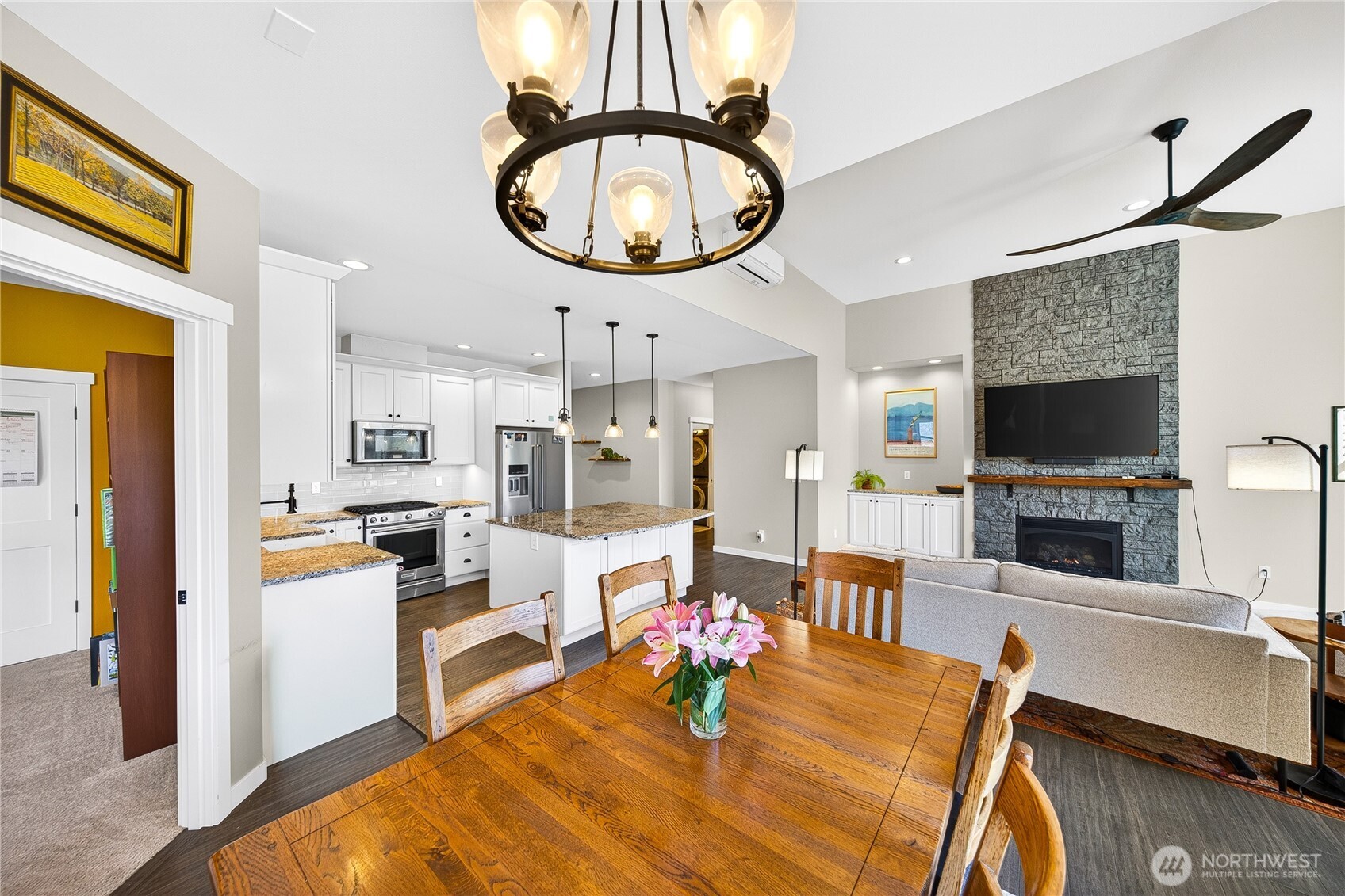 1268 Curtis Way Freeland, WA 98249 - Photo 15 of 40 a view of a dining room kitchen with furniture a fireplace wooden floor and a chandelier