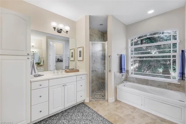 a spacious bathroom with a granite countertop sink a mirror a bathtub and shower