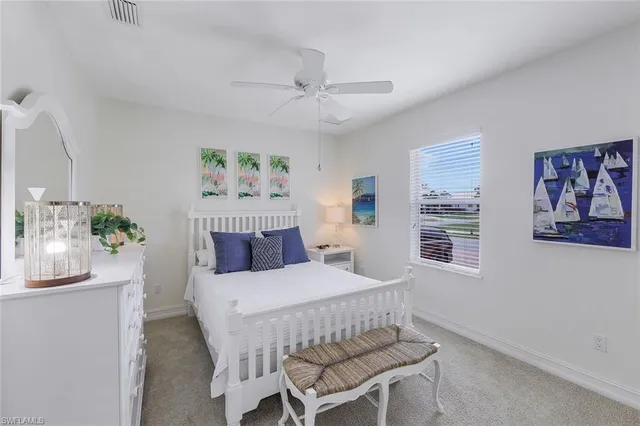 a bedroom with a bed painting on wall and a large window