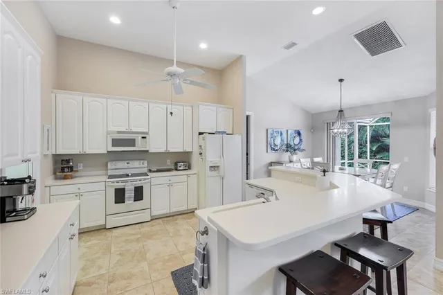 a kitchen with stainless steel appliances a stove a sink a refrigerator and white cabinets with wooden floor