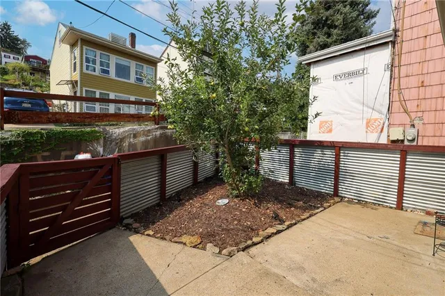 a view of a brick wall with two windows in the yard