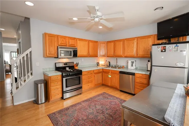 a kitchen with granite countertop a stove top oven a sink dishwasher a refrigerator and a dining table with wooden floor