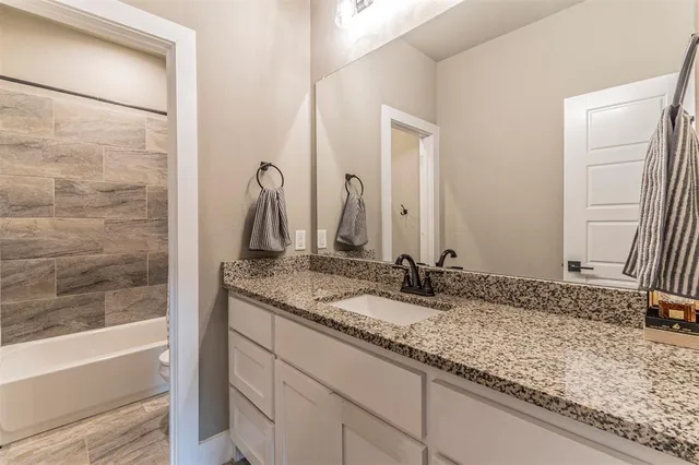 a bathroom with a granite countertop sink and a mirror