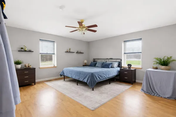 a spacious bedroom with a bed and wooden floor