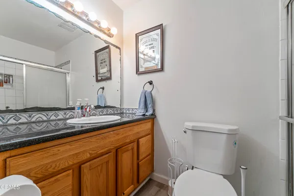 a bathroom with a granite countertop toilet sink and mirror