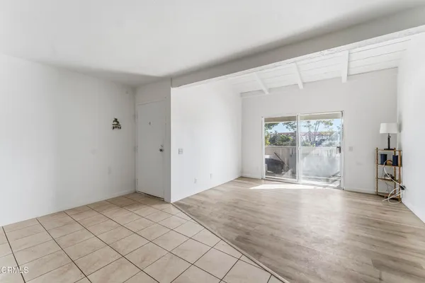 a view of an empty room with window and wooden floor