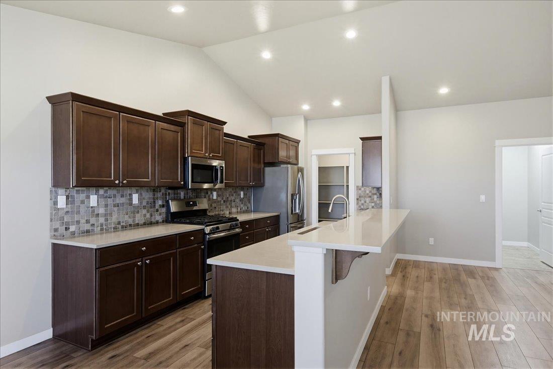 12460 West Azure Street Boise, ID 83713 - Photo 11 of 34 Kitchen featuring dark wood cabinetry, light countertops, and a mosaic tile backsplash
