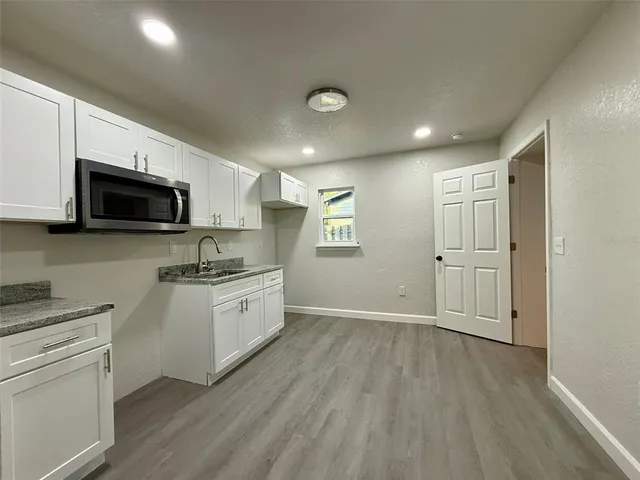 a large kitchen with cabinets wooden floor and stainless steel appliances