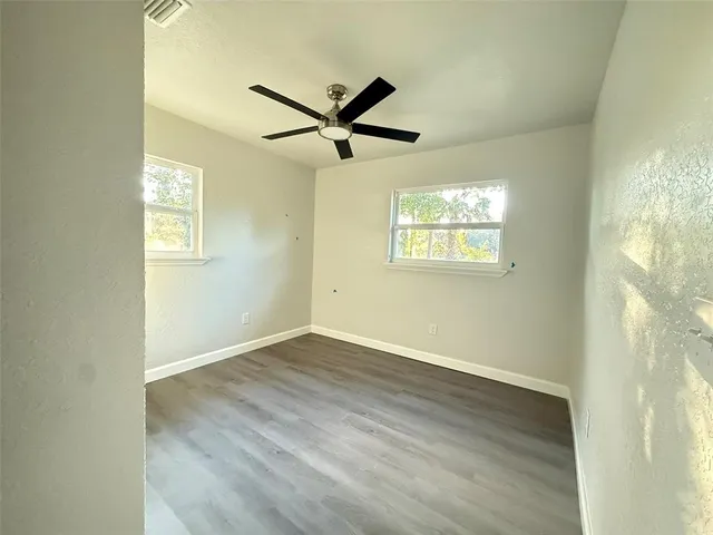 a view of empty room with wooden floor and fan