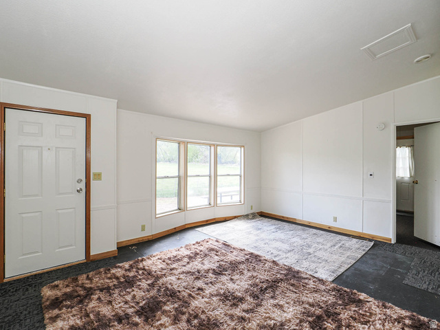 94 Spring Canyon Road Coalville, UT 84017 - Photo 28 of 50 Spacious interior featuring a white four-panel entry door with wood trim, multiple windows providing natural light, and contrasting dark flooring