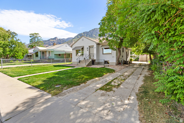 372 800 East Provo, UT 84606 - Photo 25 of 29 White exterior residence featuring a front lawn, mature trees, concrete driveway, and a partially covered front porch