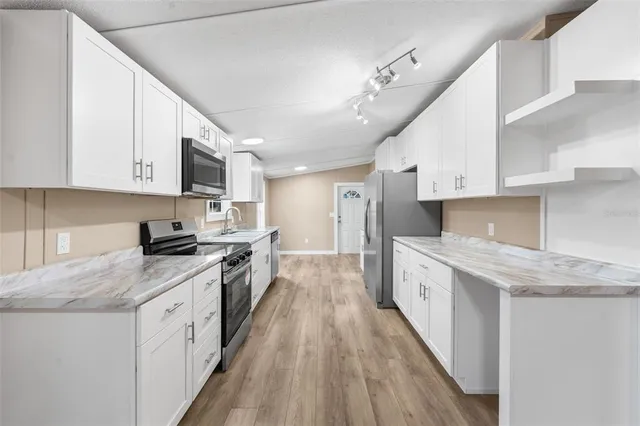 a large kitchen with stainless steel appliances granite countertop a lot of counter space a sink and dishwasher a stove top oven with wooden floor