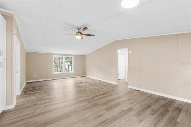 a view of an empty room with a window and wooden floor