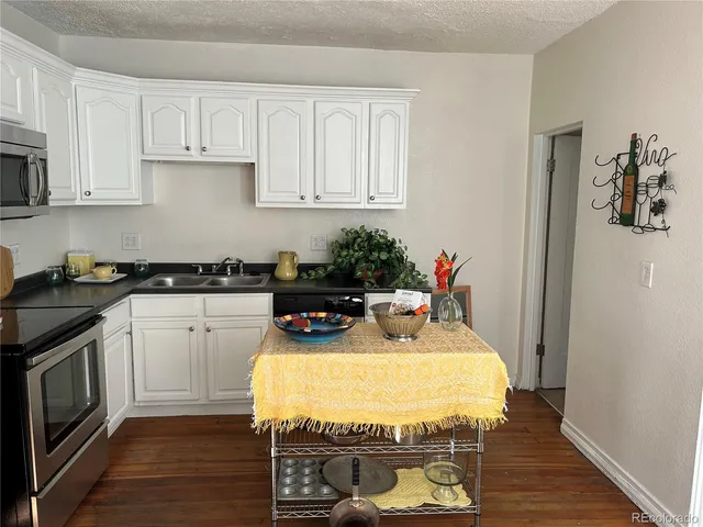 a kitchen with granite countertop white cabinets and stainless steel appliances
