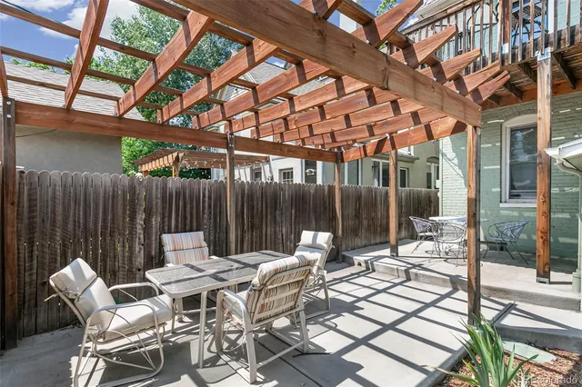 a view of a backyard with table and chairs under an umbrella with wooden fence
