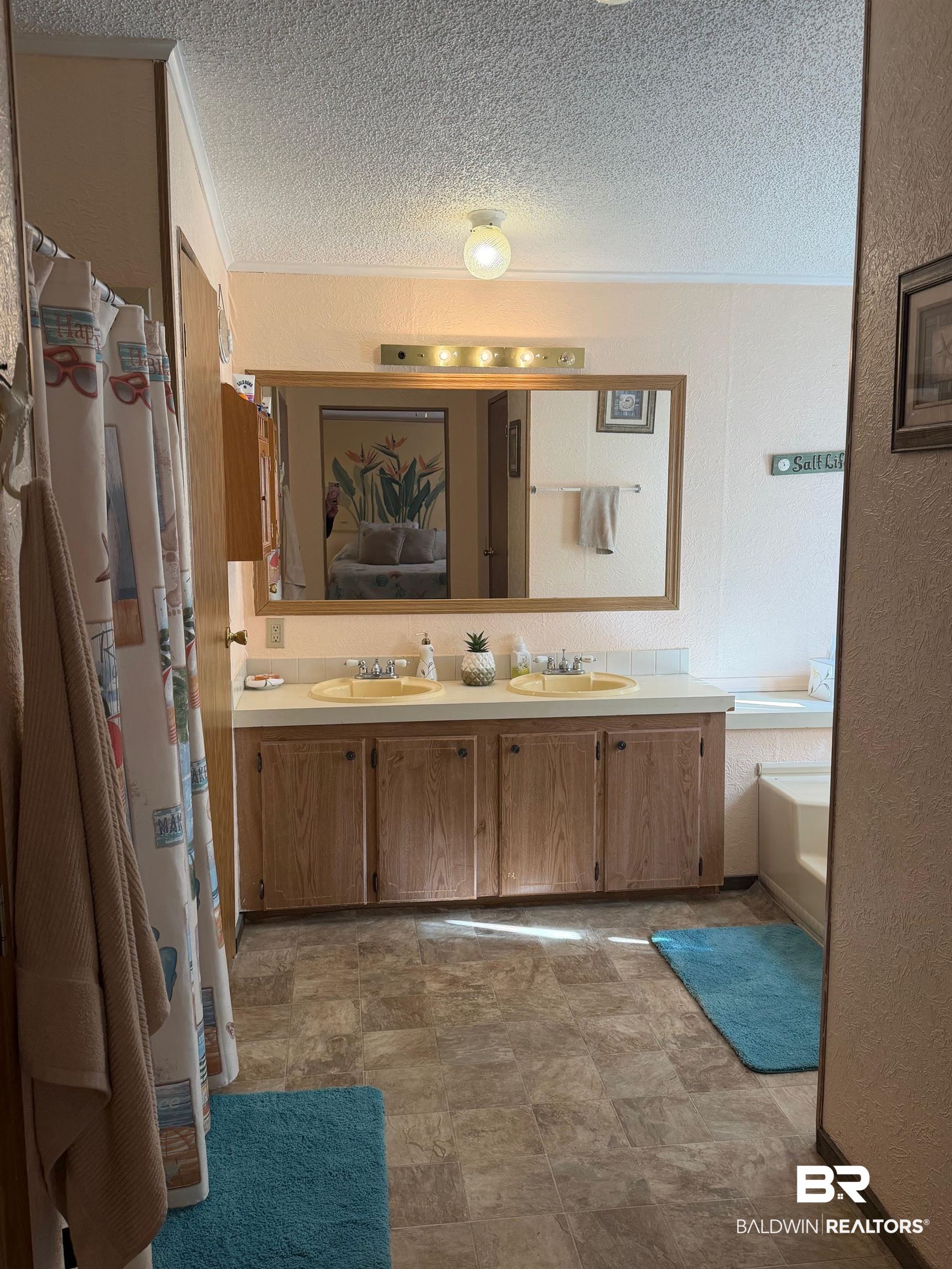 1127 Ridgewood Drive Lillian, AL 36549 - Photo 8 of 32 Full bath featuring double vanity, a textured ceiling, a textured wall, ensuite bathroom, and a shower with curtain