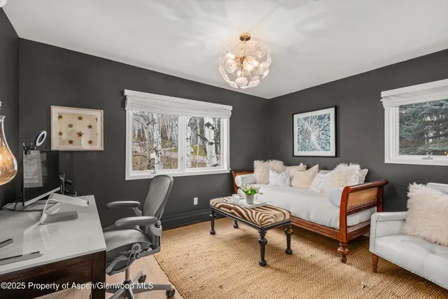 a view of a patio with couches table and chairs under an umbrella with large trees