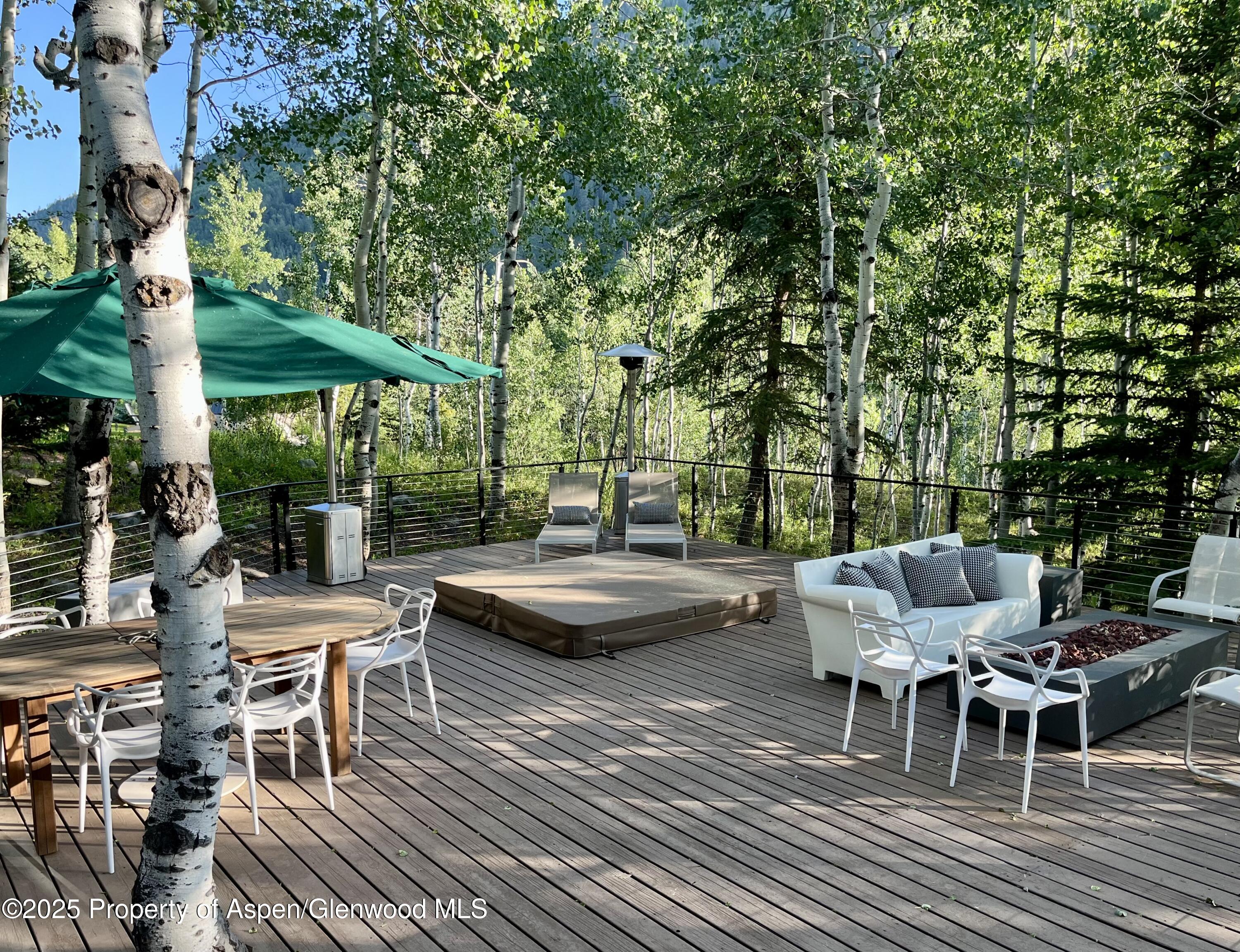 262 Eastwood Road Aspen, CO 81611 - Photo 44 of 46 a view of a patio with couches table and chairs under an umbrella with large trees