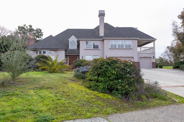 a view of a white house with a yard and potted plants
