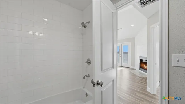 a view of an empty room with window and wooden floor