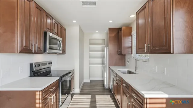 a kitchen with stainless steel appliances a stove a sink and a microwave