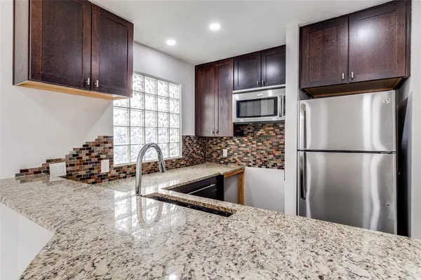 a kitchen with granite countertop stainless steel appliances a refrigerator and a sink