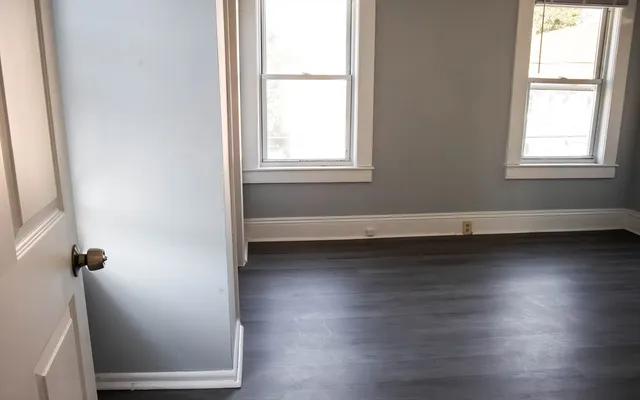 an empty room with wooden floor and windows