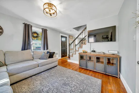 a living room with stainless steel appliances furniture and a flat screen tv