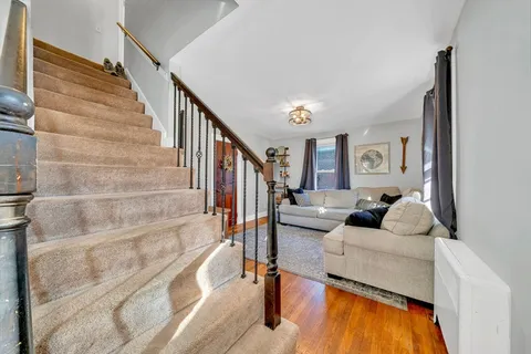 a living room with couches and a dining table with wooden floor