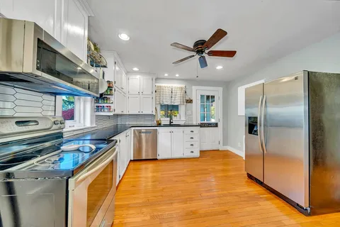 a large kitchen with stainless steel appliances granite countertop a sink a stove and a refrigerator