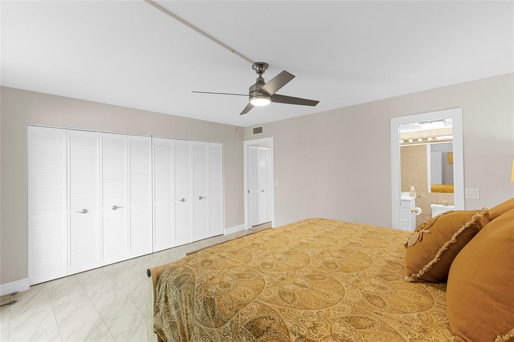3028 Cambridge B, Unit 3028 Deerfield Beach, FL 33442 - Photo 17 of 49 a bedroom with a large bed and a chandelier fan