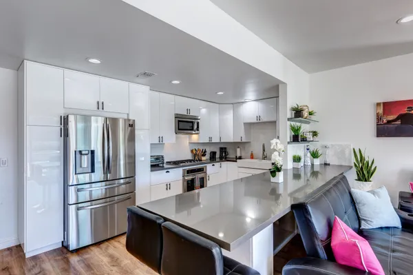 a kitchen with stainless steel appliances granite countertop a refrigerator a stove a sink a dining table and chairs