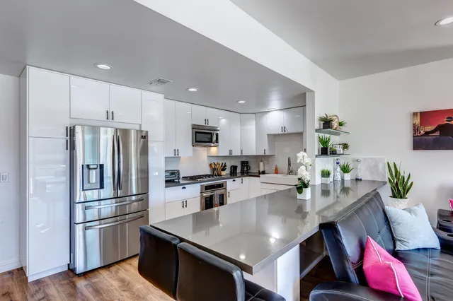 a kitchen with stainless steel appliances granite countertop a refrigerator a stove a sink a dining table and chairs