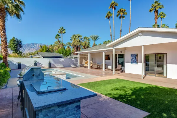 a view of a house with backyard sitting area and swimming pool