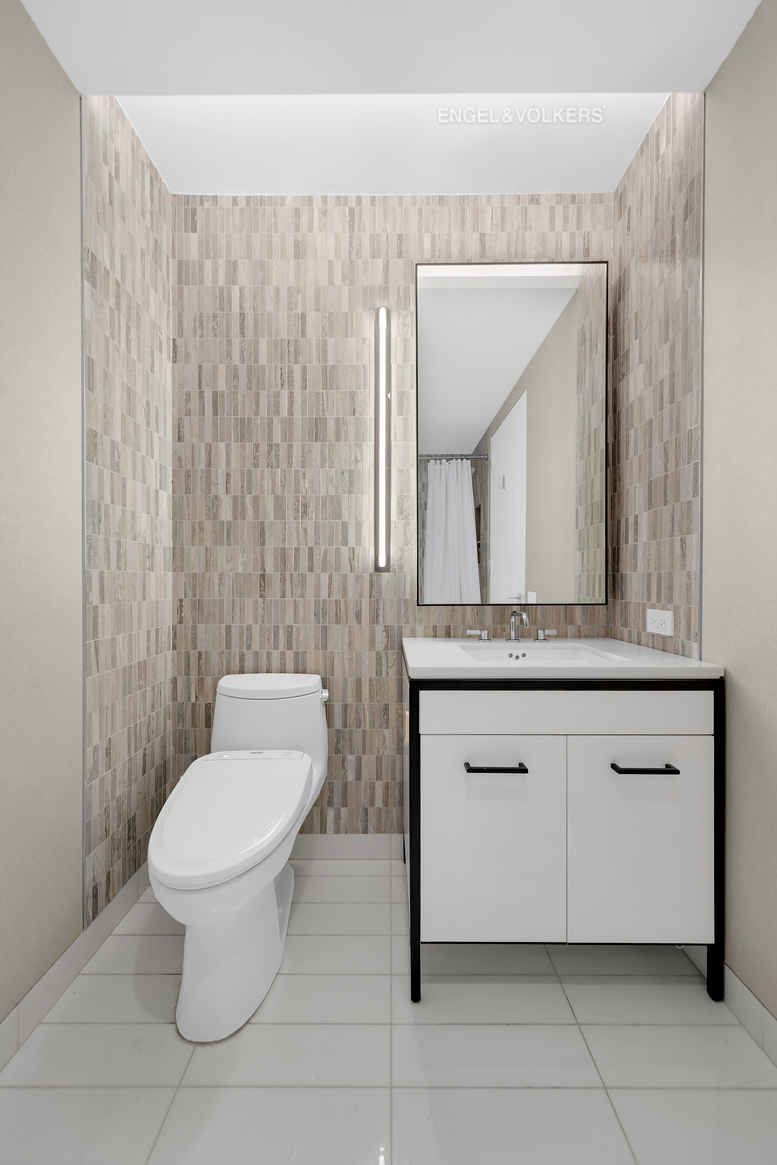 70 Charlton Street, Unit 21C Manhattan, NY 10014 - Photo 14 of 22 a bathroom with a toilet a sink and mirror