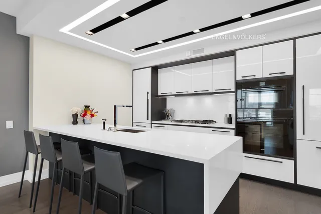 a kitchen with stainless steel appliances a white stove top oven a sink a dining table and chairs with wooden floor