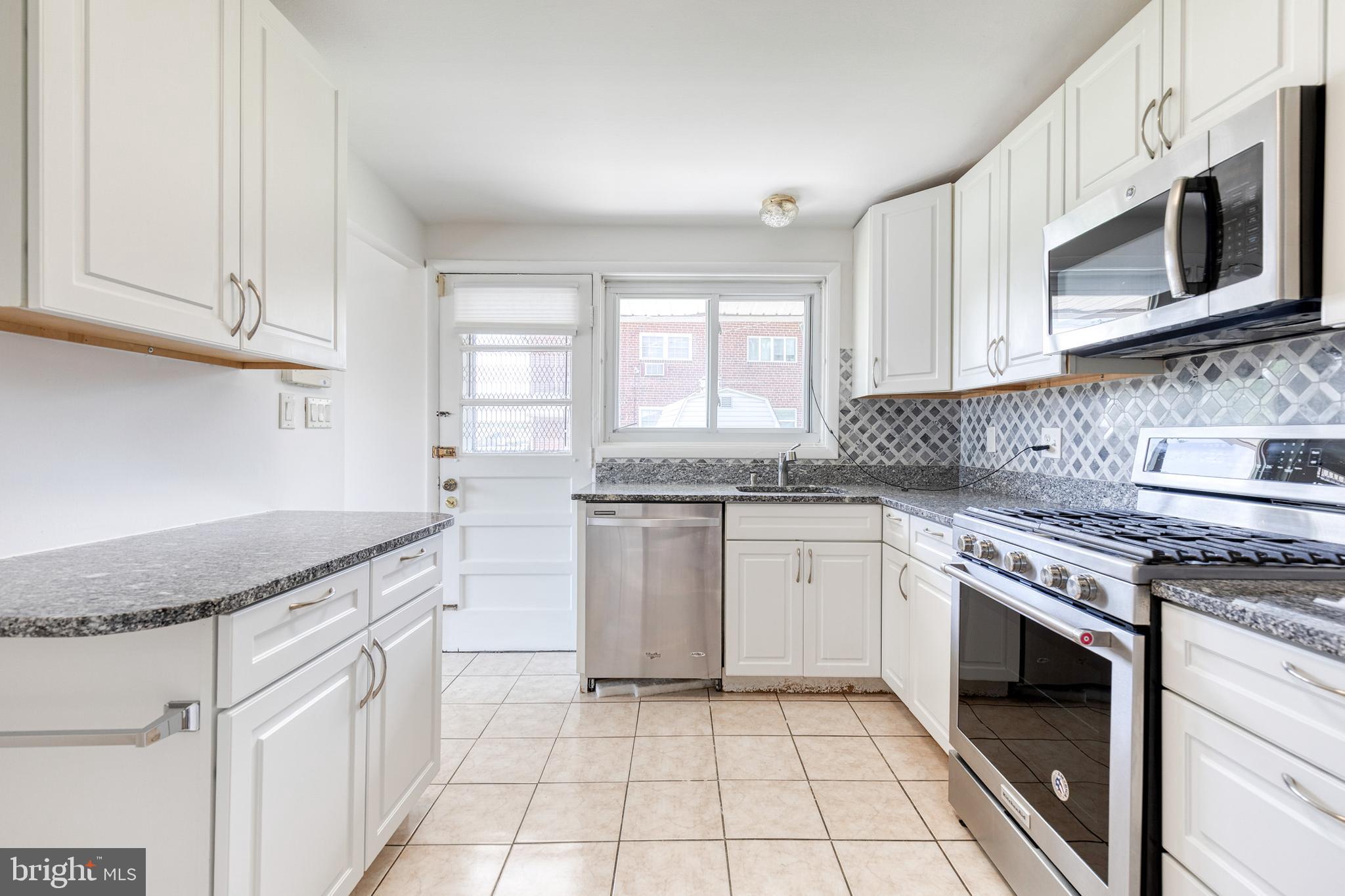 6653 Chippewa Drive Baltimore, MD 21209 - Photo 12 of 24 a kitchen with granite countertop white cabinets stainless steel appliances a sink and a window
