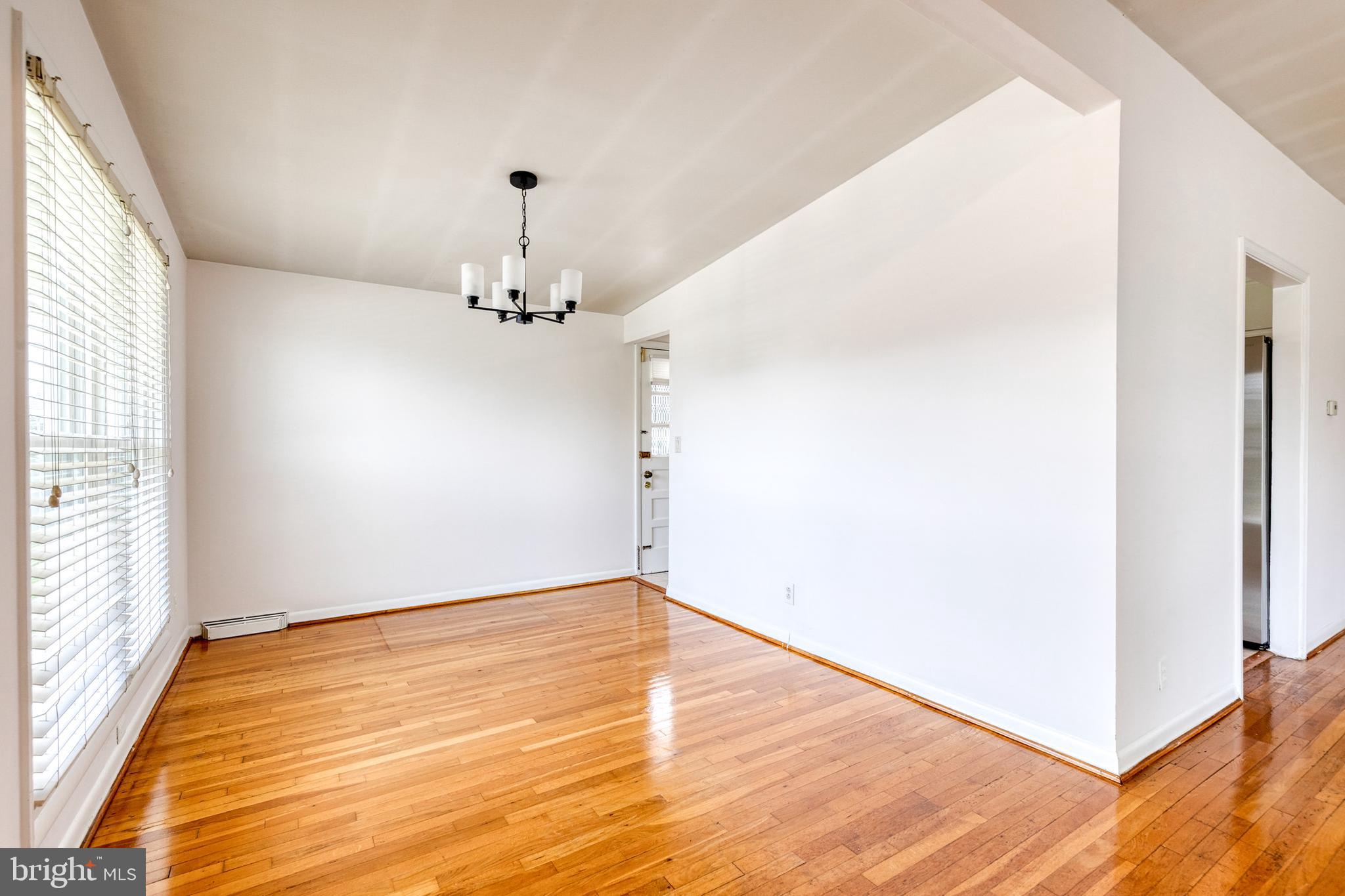6653 Chippewa Drive Baltimore, MD 21209 - Photo 7 of 24 an empty room with wooden floor chandelier and windows